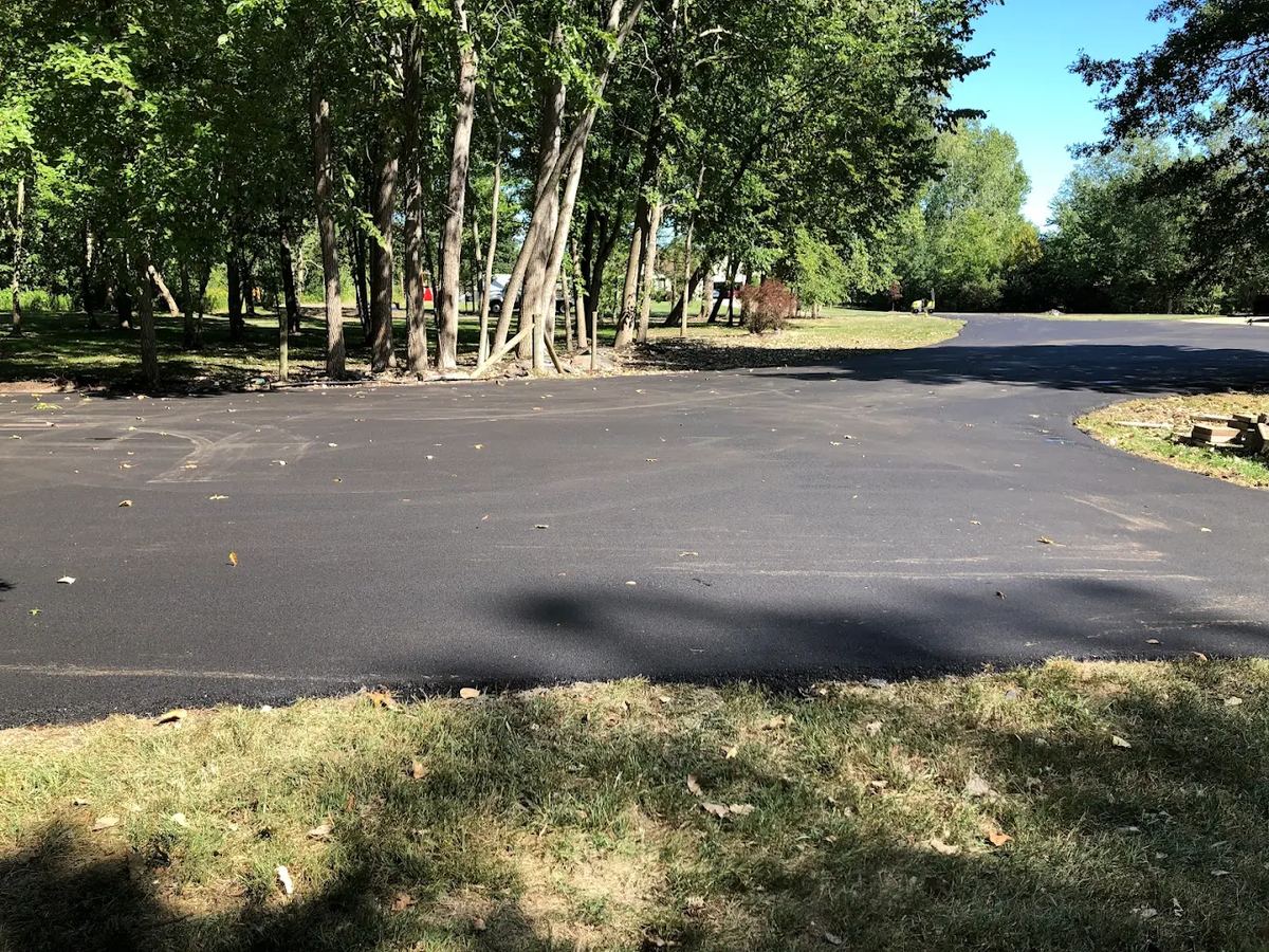 Curved residential asphalt driveway with landscaping