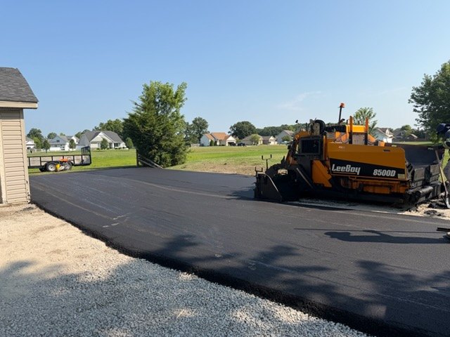 New asphalt driveway up to an attached garage