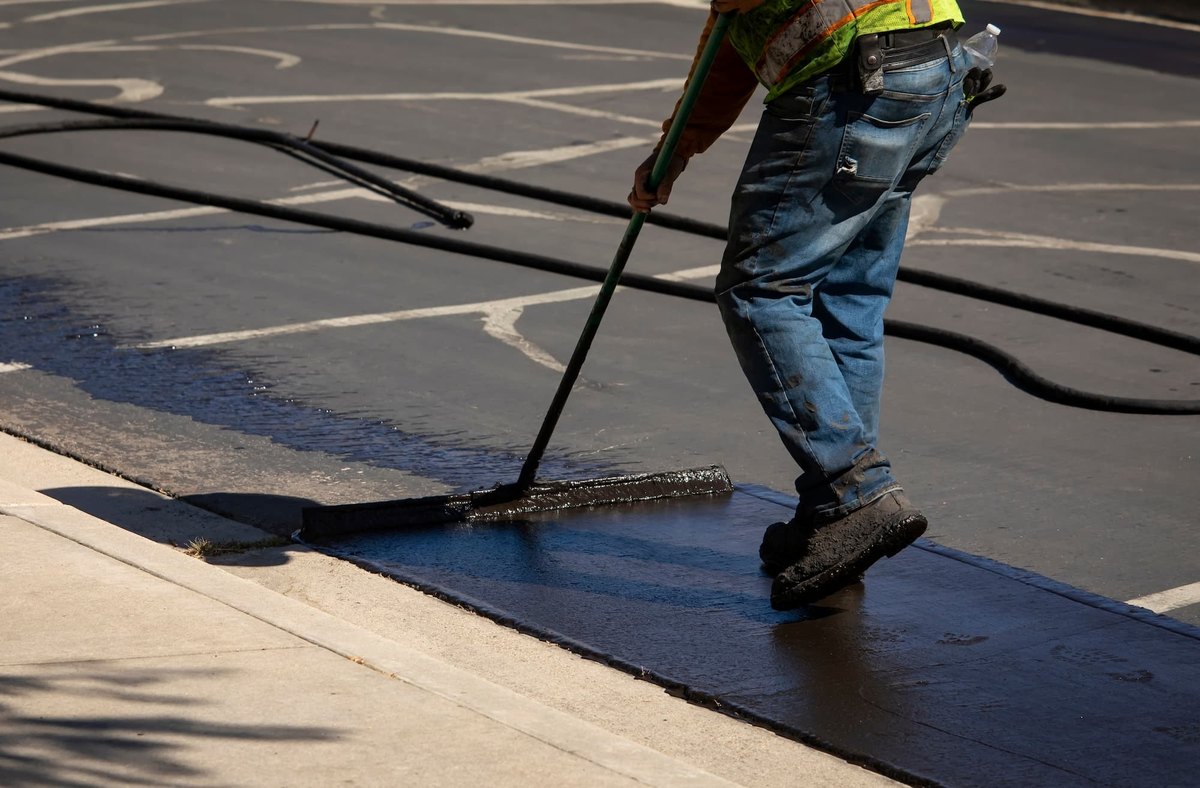 Crew applying fresh sealcoat to an asphalt surface
